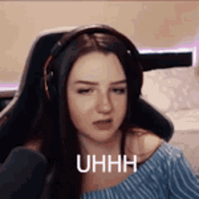 a woman wearing headphones is sitting in a gaming chair .