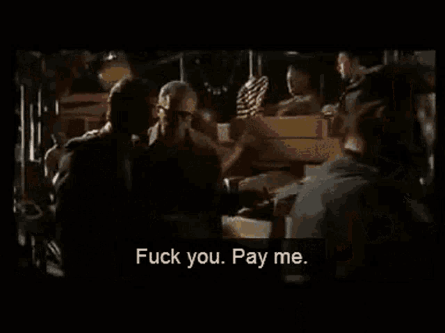 a group of people standing in a dark room with a man saying " fuck you pay me "