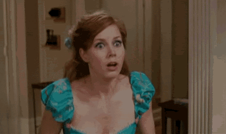 a woman in a blue dress is making a surprised face in a room .