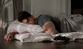 a man is laying on a pillow on the floor next to a game controller