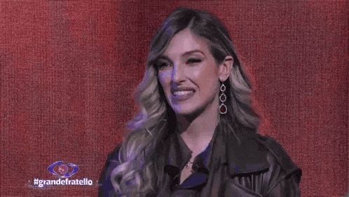 a woman wearing a leather jacket and earrings is smiling .