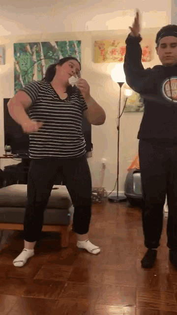 a woman in a striped shirt is dancing with a man in a black sweatshirt