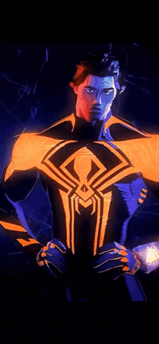 a man in a spiderman costume with a spider on his chest is standing in the dark .