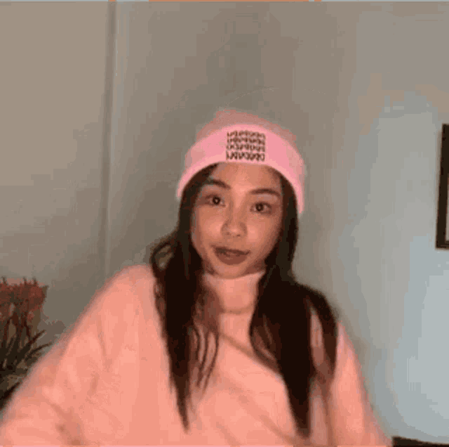 a girl wearing a pink hat and a pink sweater is smiling .