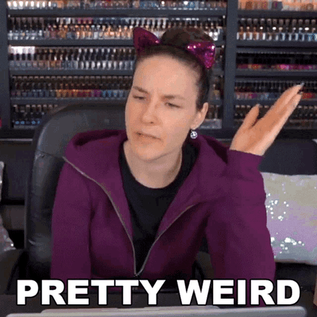 a woman in a purple jacket is sitting in front of a laptop with the words pretty weird on the screen