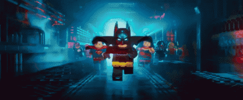 a group of lego batman , superman , wonder woman and robin are walking down a dark street .
