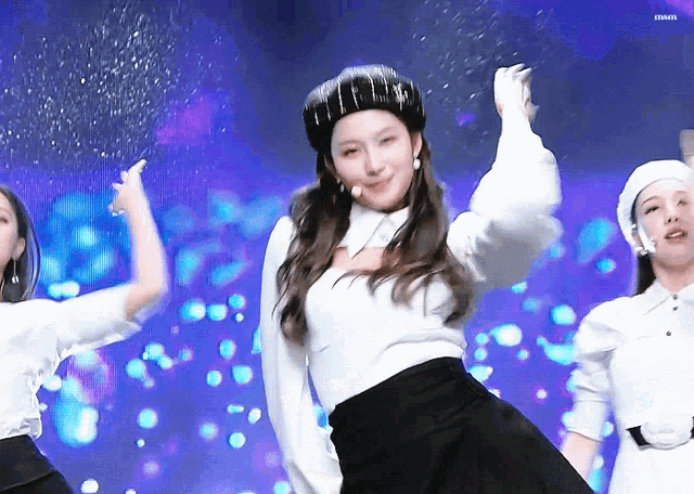 a woman wearing a beret and a white shirt is dancing on a stage