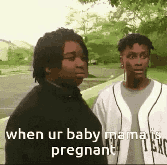a couple of men are standing next to each other on a sidewalk and one of them is pregnant .