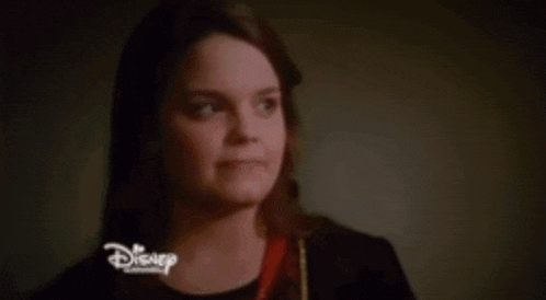a woman in a red dress and black coat is standing in a dark room .