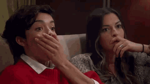a woman is covering her mouth with her hand while watching a movie .