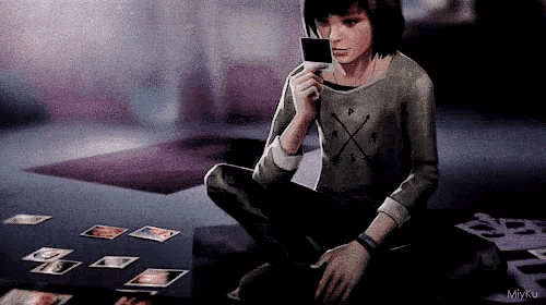 a video game character is sitting on the floor holding a card