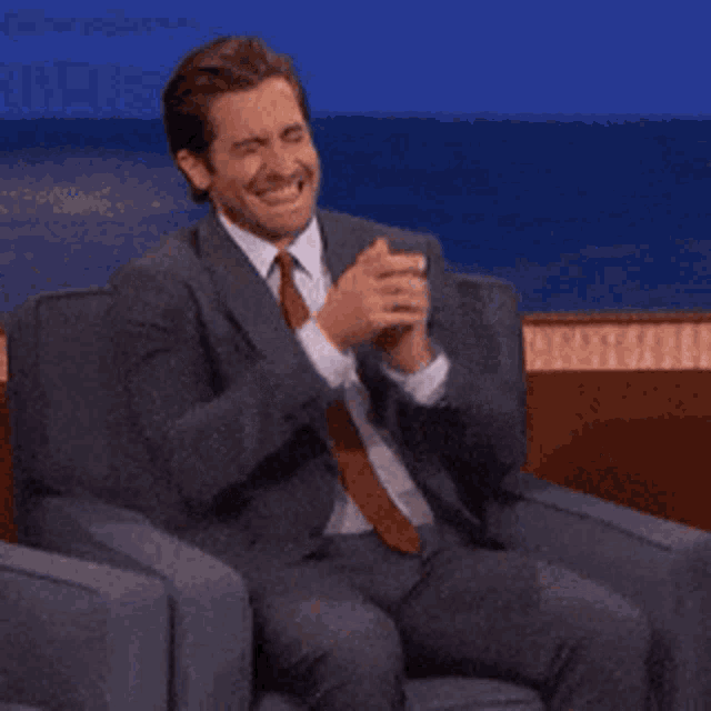 a man in a suit and tie sits in a chair