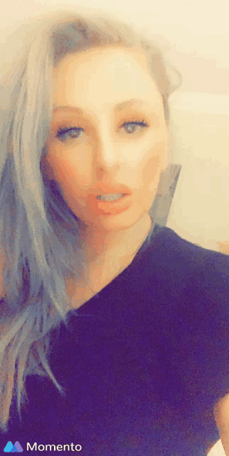 a woman in a black shirt is taking a selfie with the words momento on the bottom right