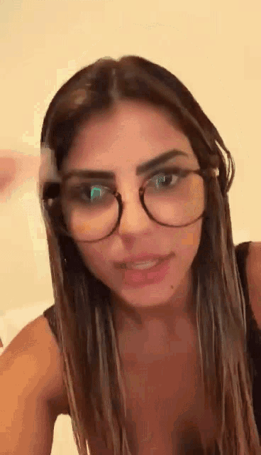 a close up of a woman wearing glasses and a bra .