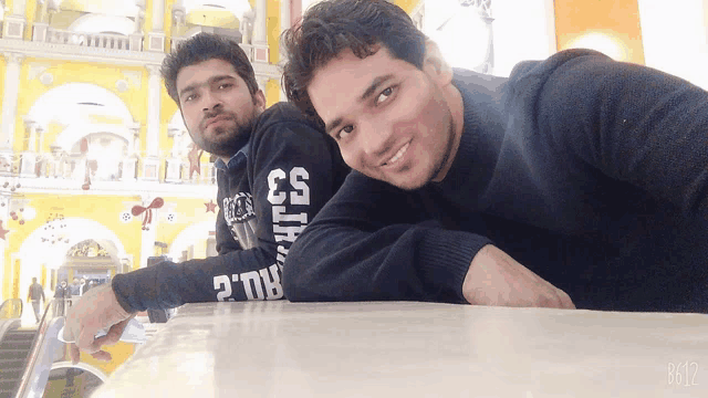 two men are posing for a picture with one wearing a sweater that says 33