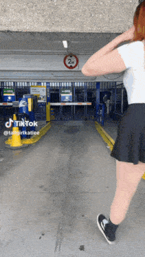 a woman is standing in a parking garage with a sign that says 24