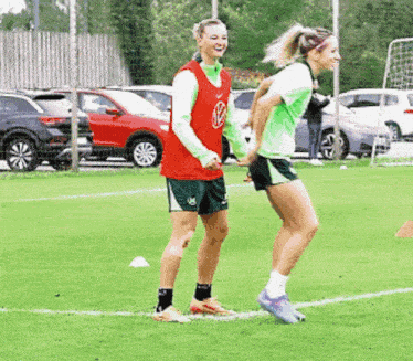 two female soccer players are standing on a field holding hands and smiling