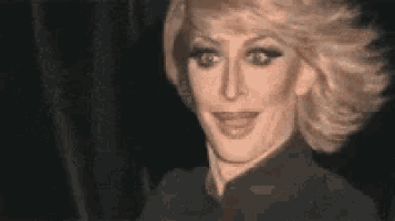 a close up of a woman 's face with blonde hair and a black shirt .