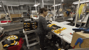 a woman working in a factory with a jersey that says ' boston bruins ' on the front