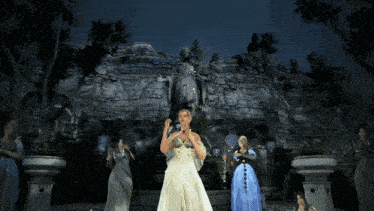 a woman in a white dress is surrounded by other women