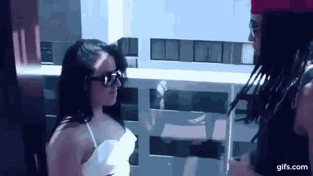 a man and a woman are standing next to each other on a balcony . the woman is wearing sunglasses .