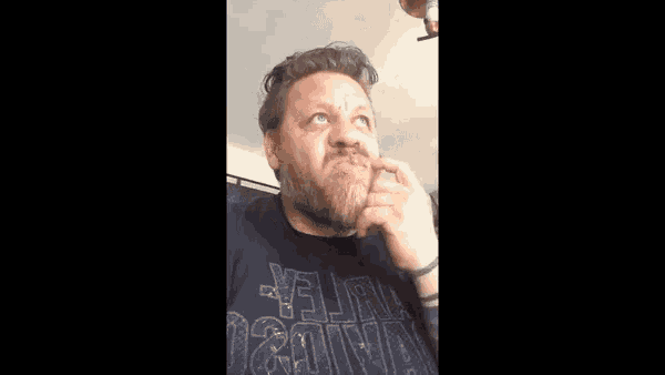 a man with a beard is making a funny face while wearing a t-shirt that says .