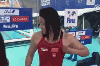 a woman in a red speedo swimsuit stands in front of a sign for fina
