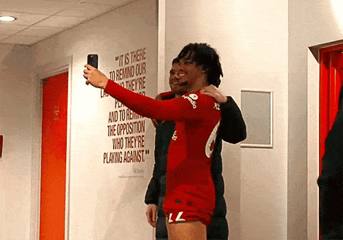 a man taking a selfie in front of a wall that says " it is there to remind our players they 're "