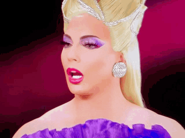 a drag queen wearing a purple dress and a crown