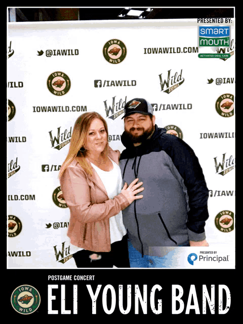 a man and a woman pose for a photo in front of a banner that says iowa wild