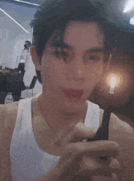 a man wearing a white tank top is holding a black object