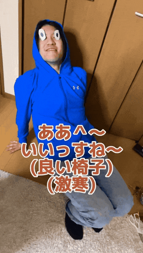 a man wearing a blue under armour hoodie is sitting on the floor