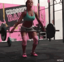 a woman lifting a barbell in front of a crossfit bar