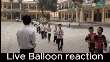 a man stands in front of a group of children with the words live balloon reaction written below him