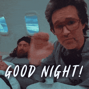 a man with glasses and a beard is laying in a bed with the words good night written below him