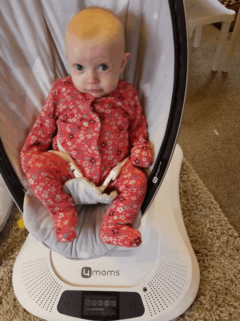 a baby sitting in a 4 moms swing