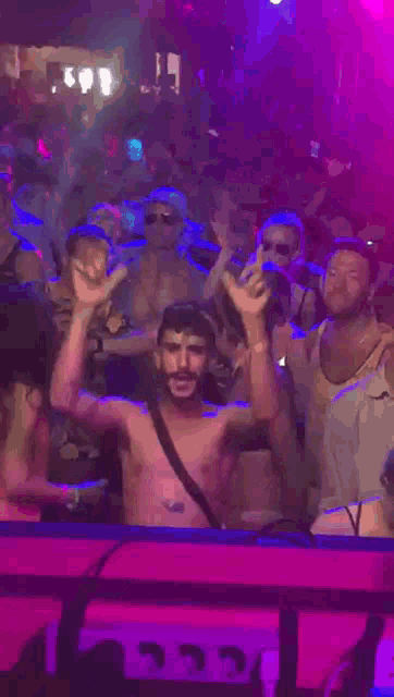 a man without a shirt is dancing in front of a crowd of people at a party .