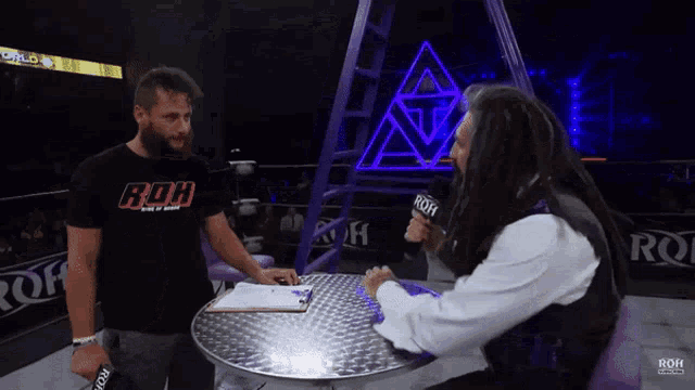 a man wearing a shirt that says roh is sitting at a table