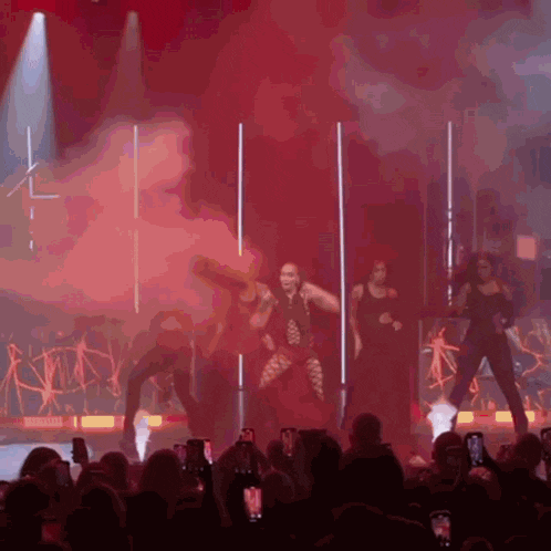 a group of women are performing on a stage with a red background