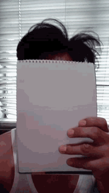 a man holds a piece of paper in front of his face