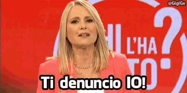 a woman in a pink jacket stands in front of a sign that says " ti denuncio io "
