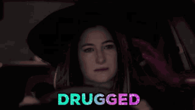 a woman in a witch costume is driving a car and the word drugged is visible .