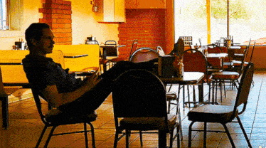 a man sits at a table in a restaurant with a sign that says burger stand on the wall