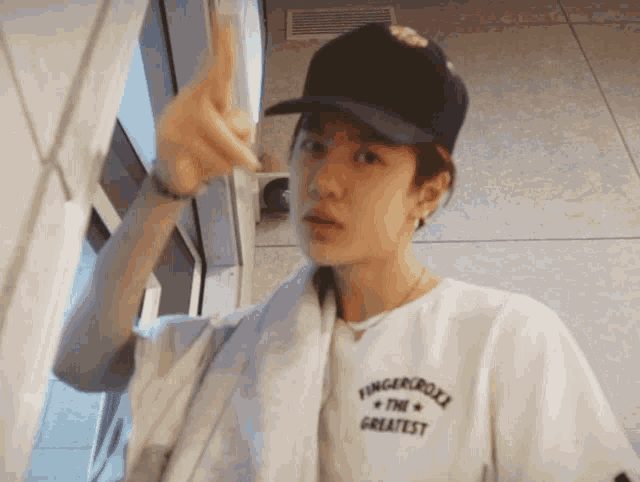 a young man wearing a hat and a white shirt that says fingerlocker