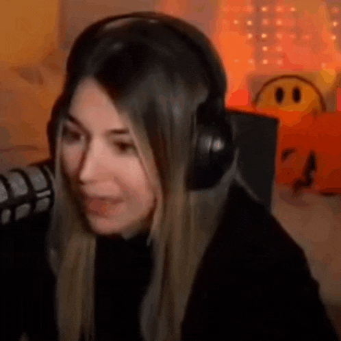 a woman wearing headphones is sitting in front of a microphone and making a funny face .