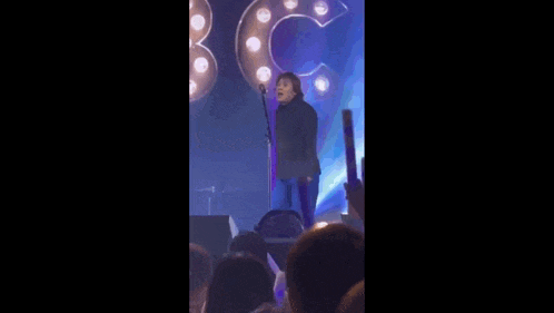 a man is singing into a microphone on a stage in front of a crowd