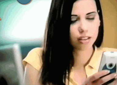a woman in a yellow shirt is holding a cell phone