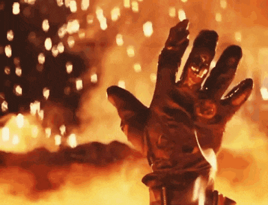 a close up of a person 's hand in a glove in front of a fire