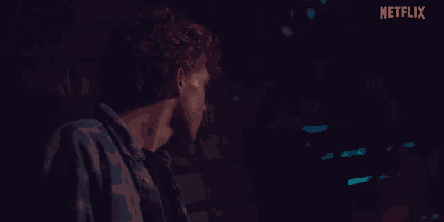 a man and a woman are looking at each other in a dark room with netflix written on the bottom