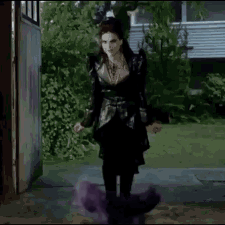 a woman in a black dress is standing in front of a door .